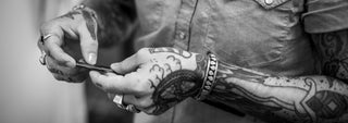 Tattooed barber hands with straight razor