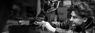 Black and white photo of guy changing oil on a motorcycle